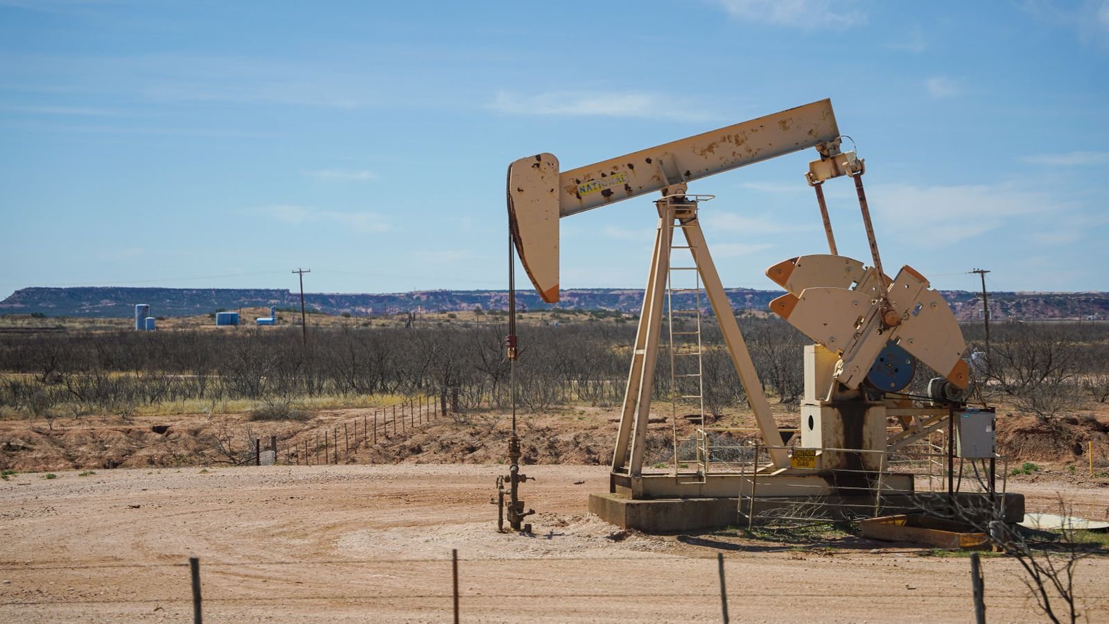 Industrial oil pumpjack extracting crude oil under a clear sky, representing surging oil prices driving market volatility