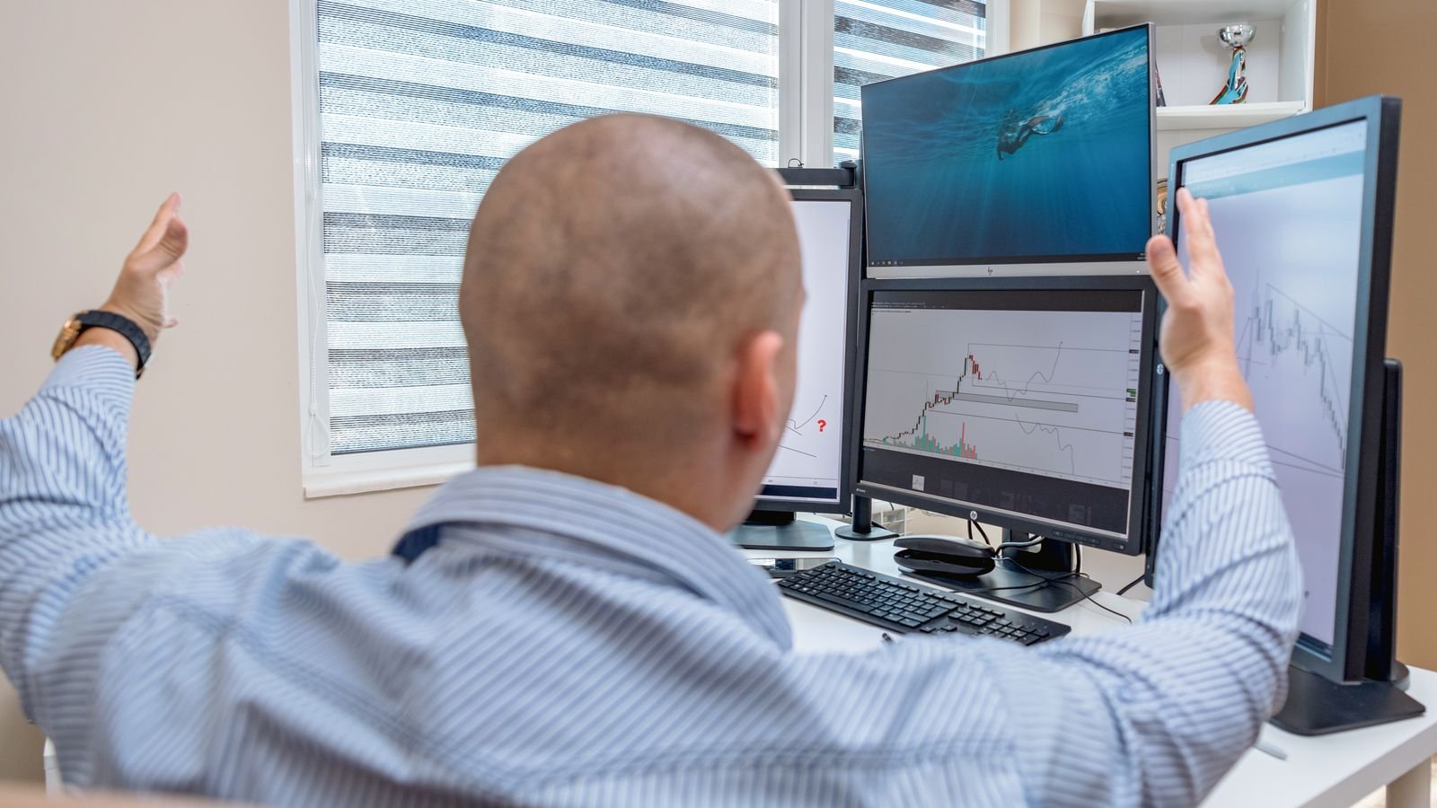 A stock trader celebrating while monitoring multiple screens with financial charts, representing this week's volatile market action
