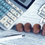 Calculator, pen and money on a table representing interest rate calculations