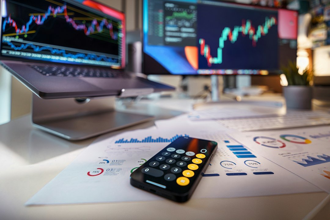 Smartphone and calculator on a desk with financial charts behind